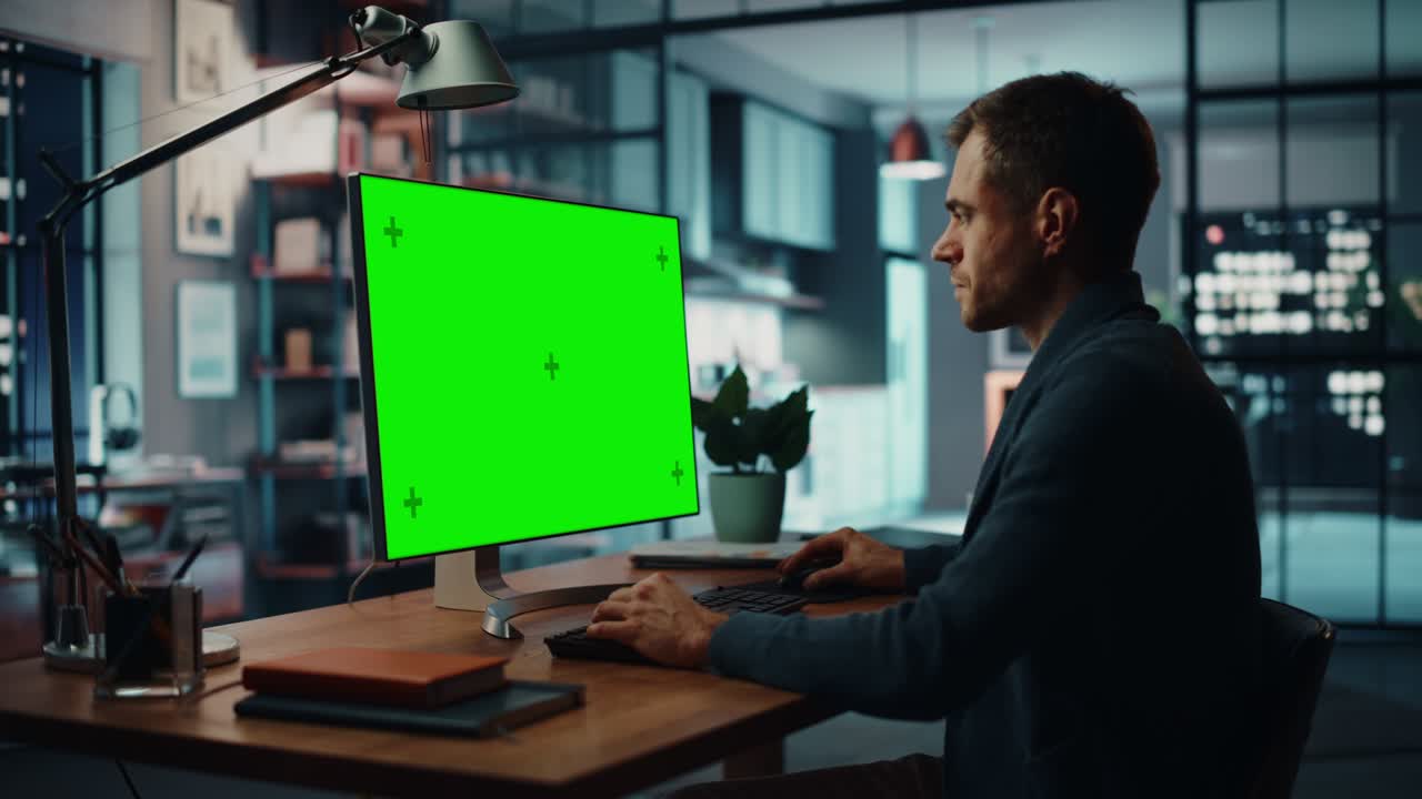 Handsome Caucasian Specialist Working on Desktop Computer with Green Screen Mock Up Display at Home Living Room. Freelance Man Chatting to Clients Over the Internet on Social Networks.