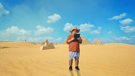 asian boy with a hat using a tablet and smiling while traveling in giza pyramid. boy researcher examines something, travel tourism adventure concept, full body