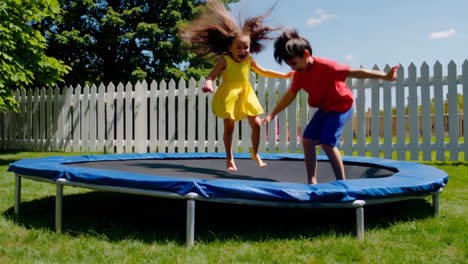 children playing and jumping on a trampoline in a backyard