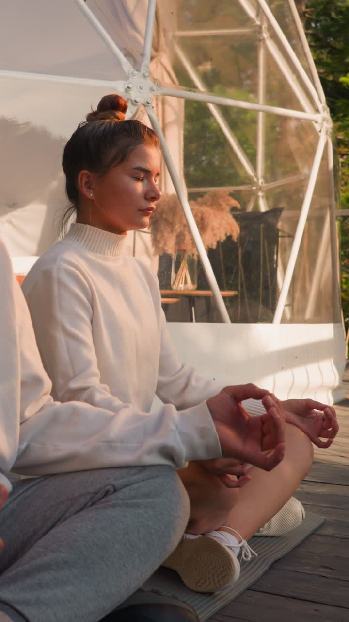 hombre y mujer se sientan en poses de loto en glamping. pareja concentrada de practicantes de yoga medita en el retiro de eco resort. armonía del cuerpo y la mente