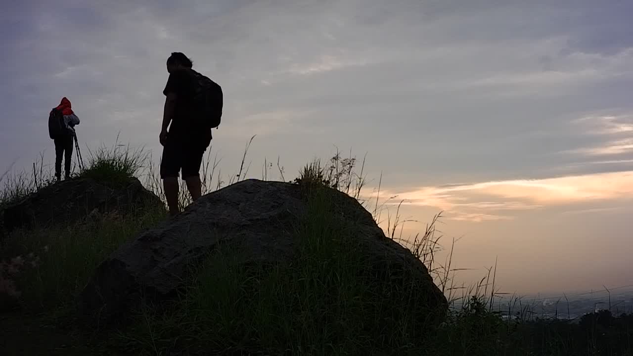 silueta de un hombre caminando por la cima de la colina para disfrutar del paisaje natural al amanecer