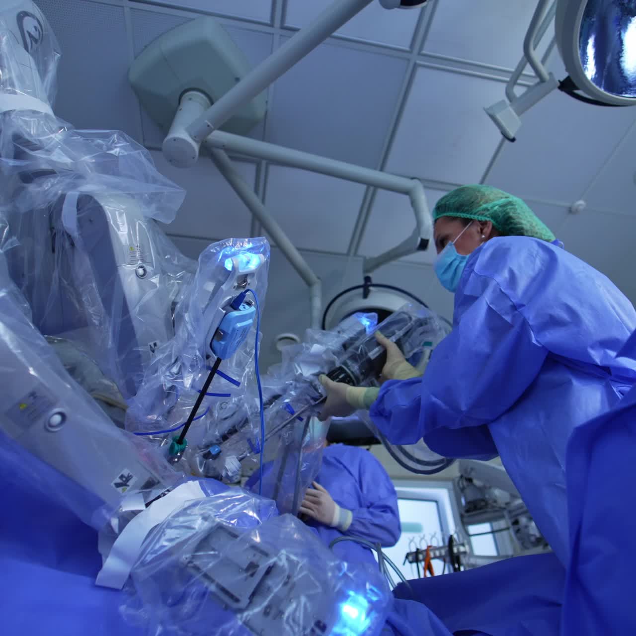 Female medic disconnecting the manipulator arm from robotic joint. Low angle sight on the innovative technological surgery equipment