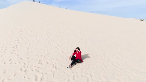 aerial view of a girl sitting on the hill in the desert.