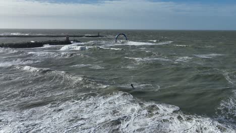 tracking drone shot of kitesurfer doing a kitleoop trick in stormy big rough waves