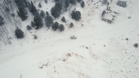 drone aerial view of land rover defender d90 suv parked on snowy backcountry alpine forest road in rocky mountains near nederland boulder colorado usa during heavy snowfall