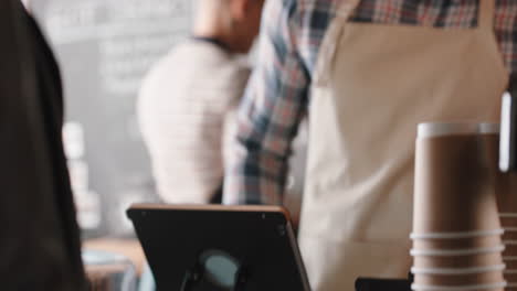 happy-barista-man-serving-customer-paying-using-smartphone-contactless-payment-spending-money-buying-coffee-in-cafe