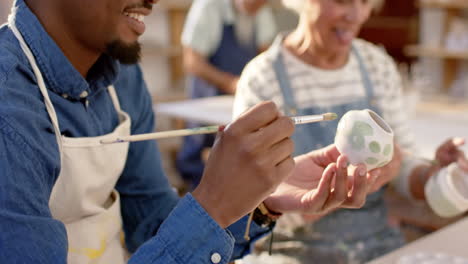 Two-diverse-male-and-female-potters-glazing-clay-jug-and-discussing-in-pottery-studio,-slow-motion