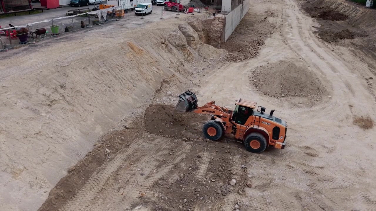 Front loader moving earth in large excavation pit at construction site