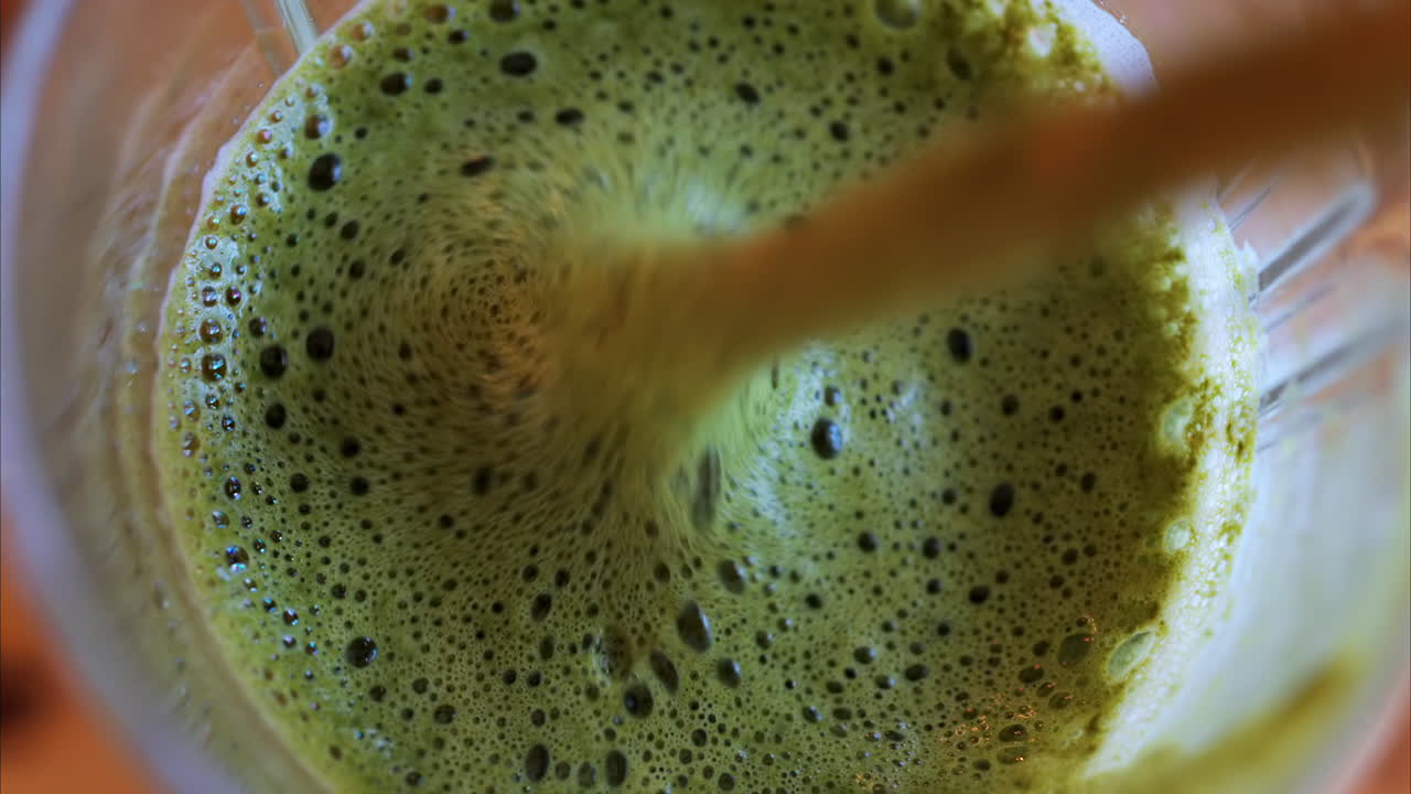 Close up of a spoon mixing in a matcha latte on a table at a cafe