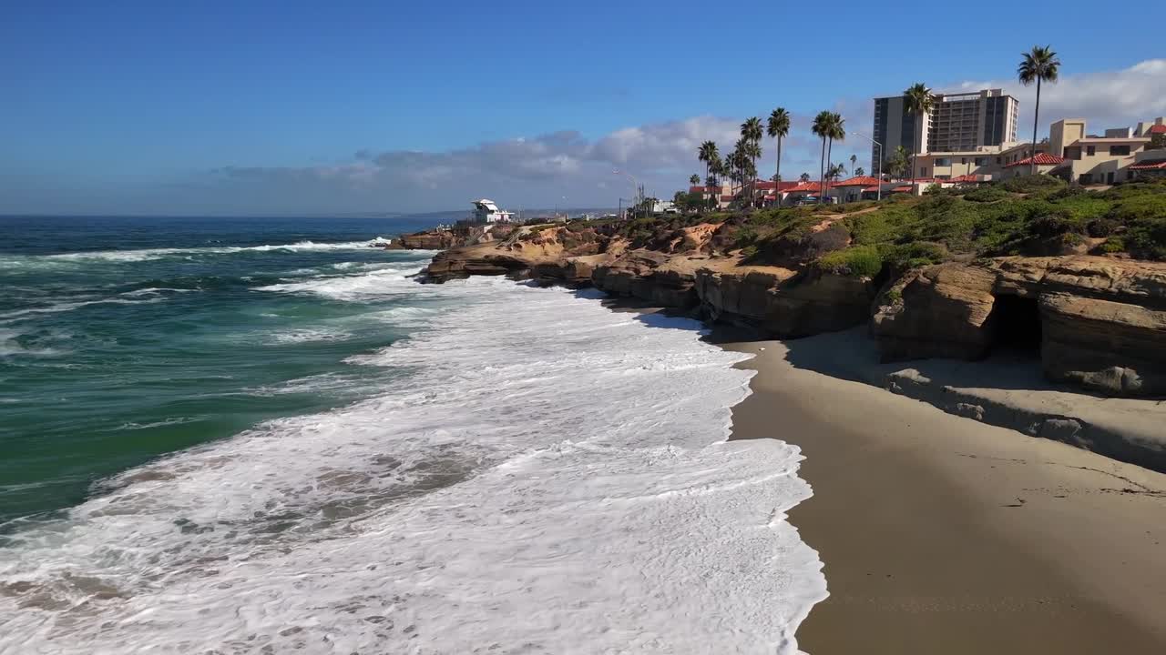 A cinematic drone shot of rhythmic waves approaching the shoreline