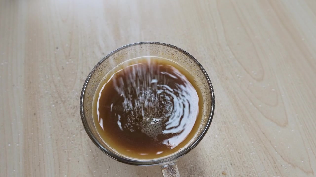 Zucchero versato in una tazza di caffè di vetro