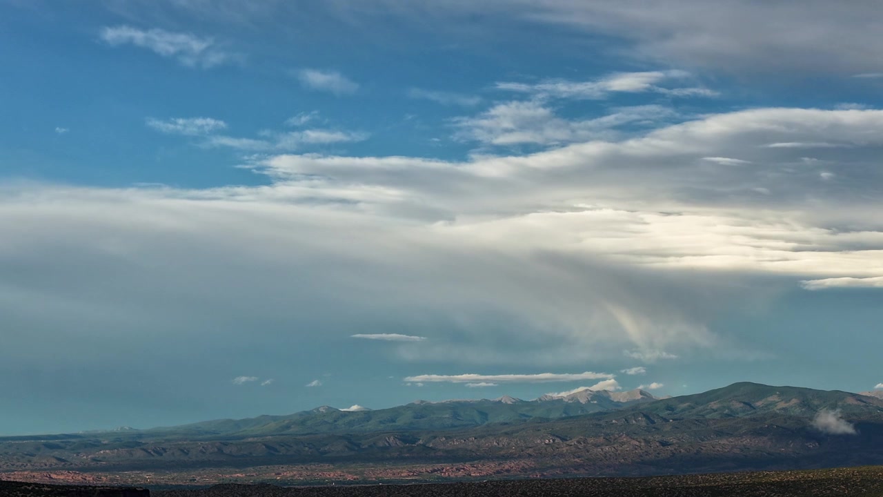 Timelapse 4K UHD con drone di un tempo cupo al crepuscolo su una vasta catena montuosa. Uno spesso strato di nuvole si muove costantemente nel cielo mentre il vapore atmosferico si condensa intorno alle cime distanti.