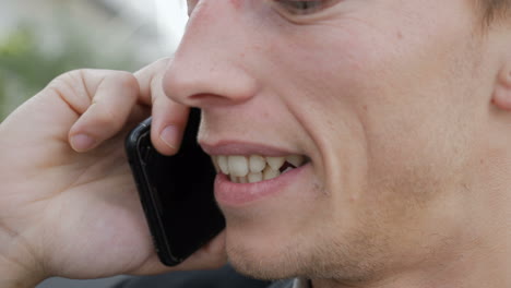 Closeup-of-young-man-talking-on-phone-outside,-looking-excited