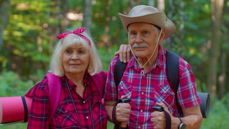 Senior-old-elderly-grandmother-grandfather-training-Nordic-walking-with-ski-trekking-poles-in-wood