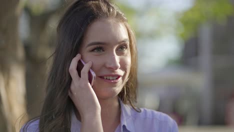 primer plano de una mujer caucásica hablando por teléfono, corrigiendo el cabello