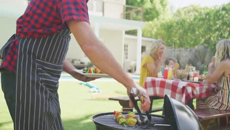 happy caucasian family having barbecue and eating in garden