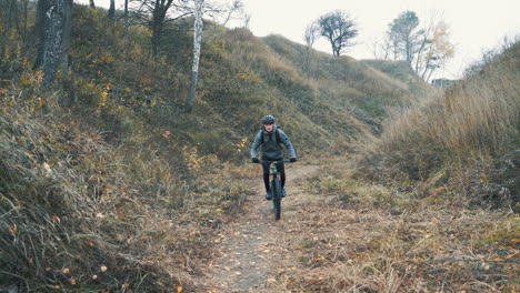 fast male cyclist with helmet riding a mountain bike down the road in the countryside