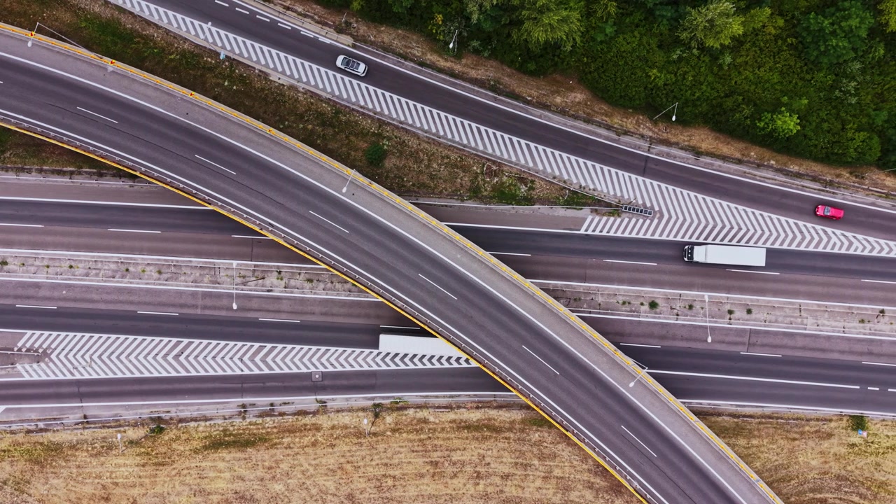 Le auto viaggiano su un'autostrada curva vicino a un'area erbosa nel pomeriggio.