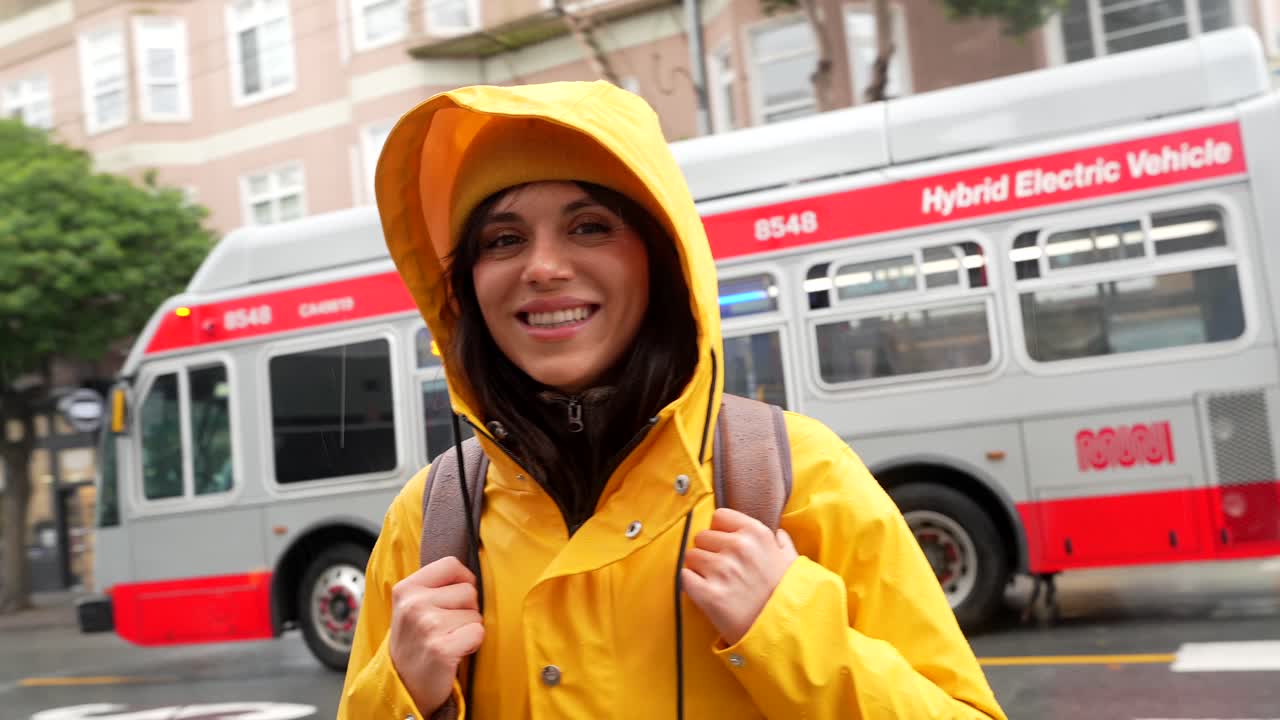Happy Young Woman in Yellow Raincoat on a Rainy City Street