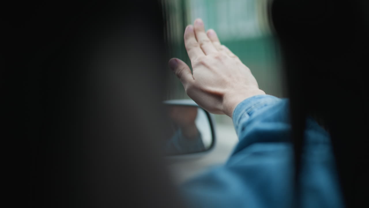 자동차 창문 장면, 자동차 창문에서 손을 흔드는 사람과 노점상의 모습이 반사되어 보이는 장면, 차량 내부에서 승객이 거울과 실루엣 효과를 통해 노점상에게 몸짓을 하는 모습