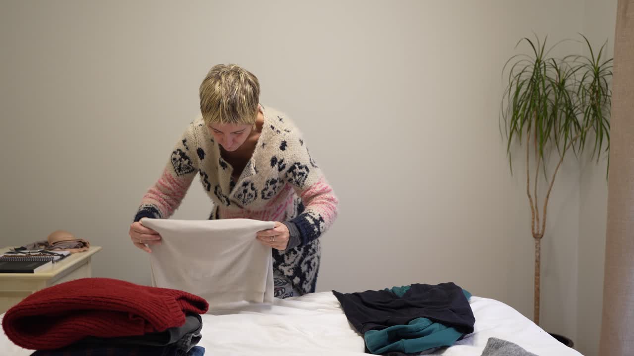 A woman folding clothes on a bed