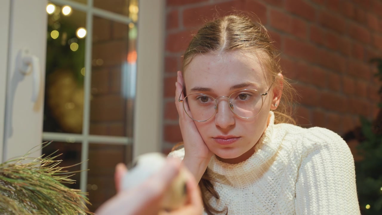 Jeune femme à lunettes regardant un petit objet dans un cadre festif