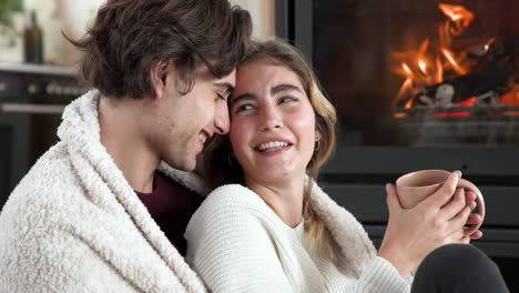 christmas time, cozy couple snuggling by fireplace, enjoying warm drinks at home