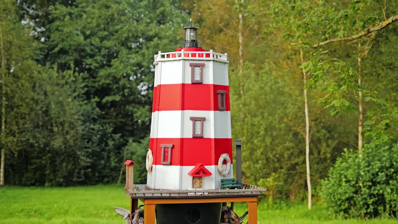 Handmade bird feeder shaped as lighthouse standing in countryside garden