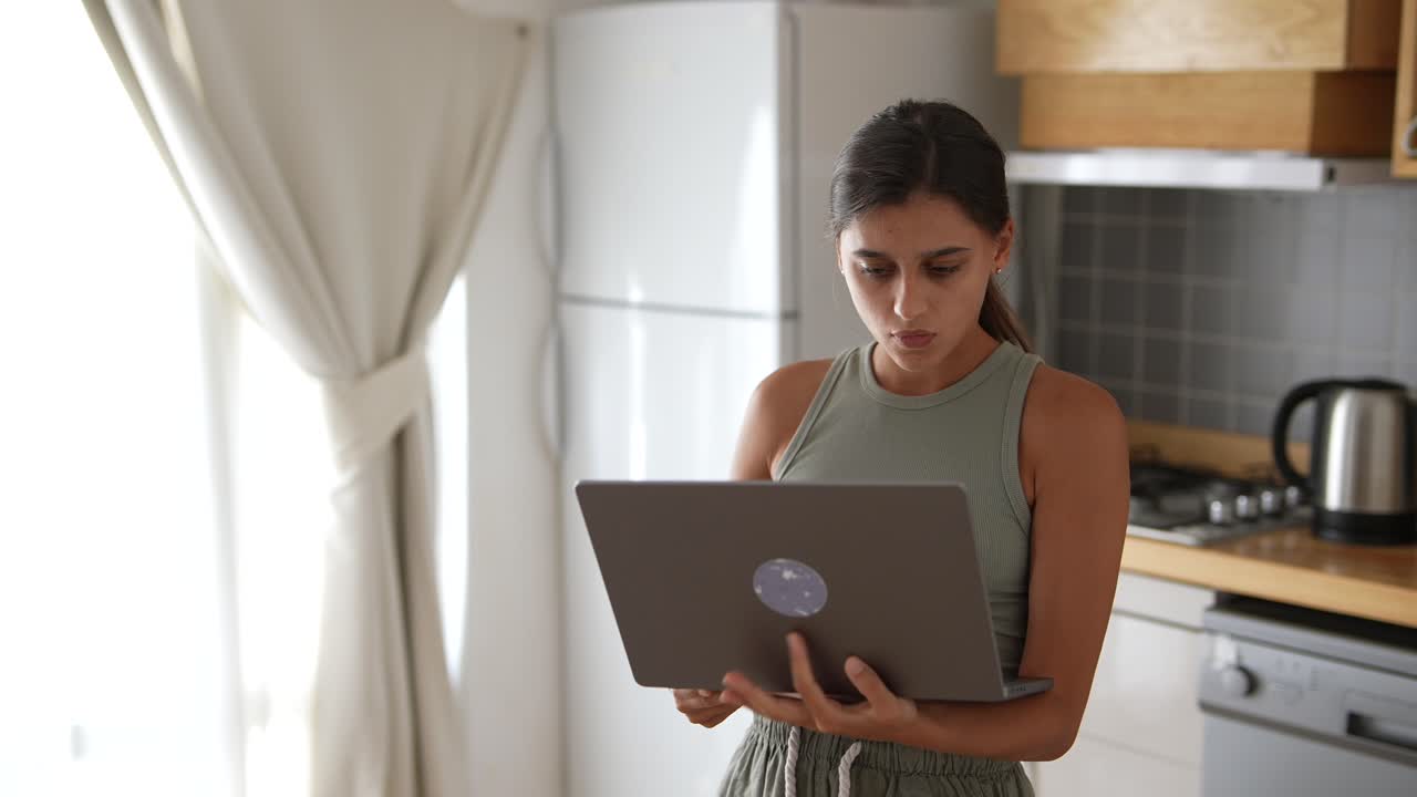 mujer trabajando en una computadora portátil en la cocina