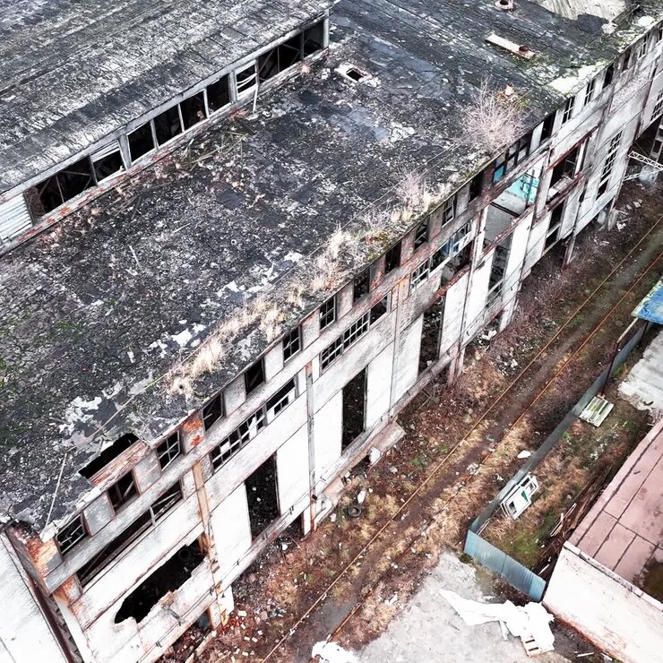 Grandi edifici di una vecchia fabbrica abbandonata, inutilizzata da molto tempo. Locali vuoti e abbandonati, senza finestre o parti delle pareti. Vista aerea