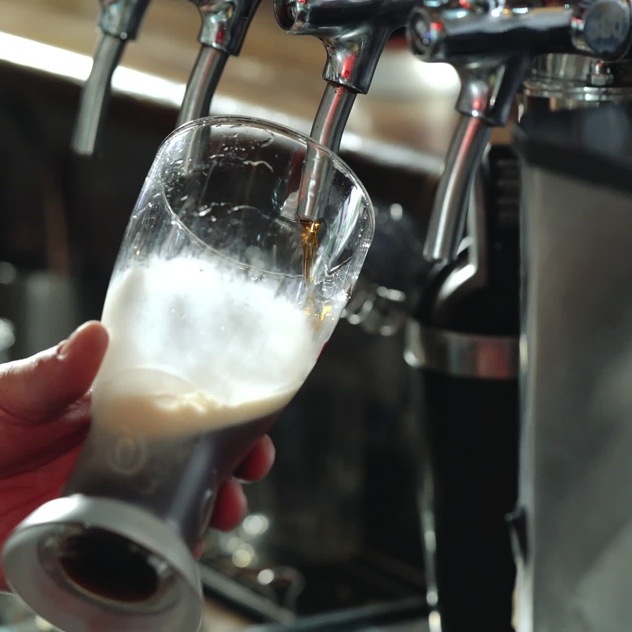 Bartender pours a dark beer in glass. Close-up. Sqare video