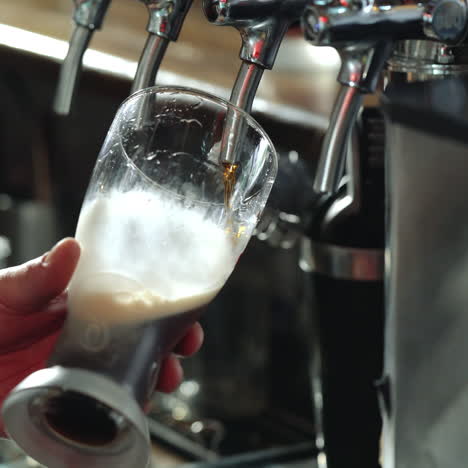 bartender pours a dark beer in glass. close-up. sqare video