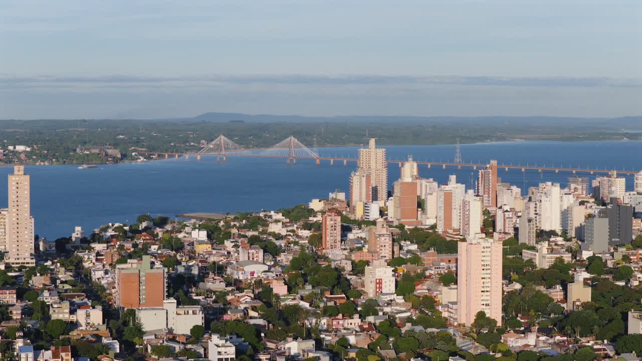 Posadas aerial cityscape with riverside skyline and the distant International bridge at sunset, Misiones, Argentina.