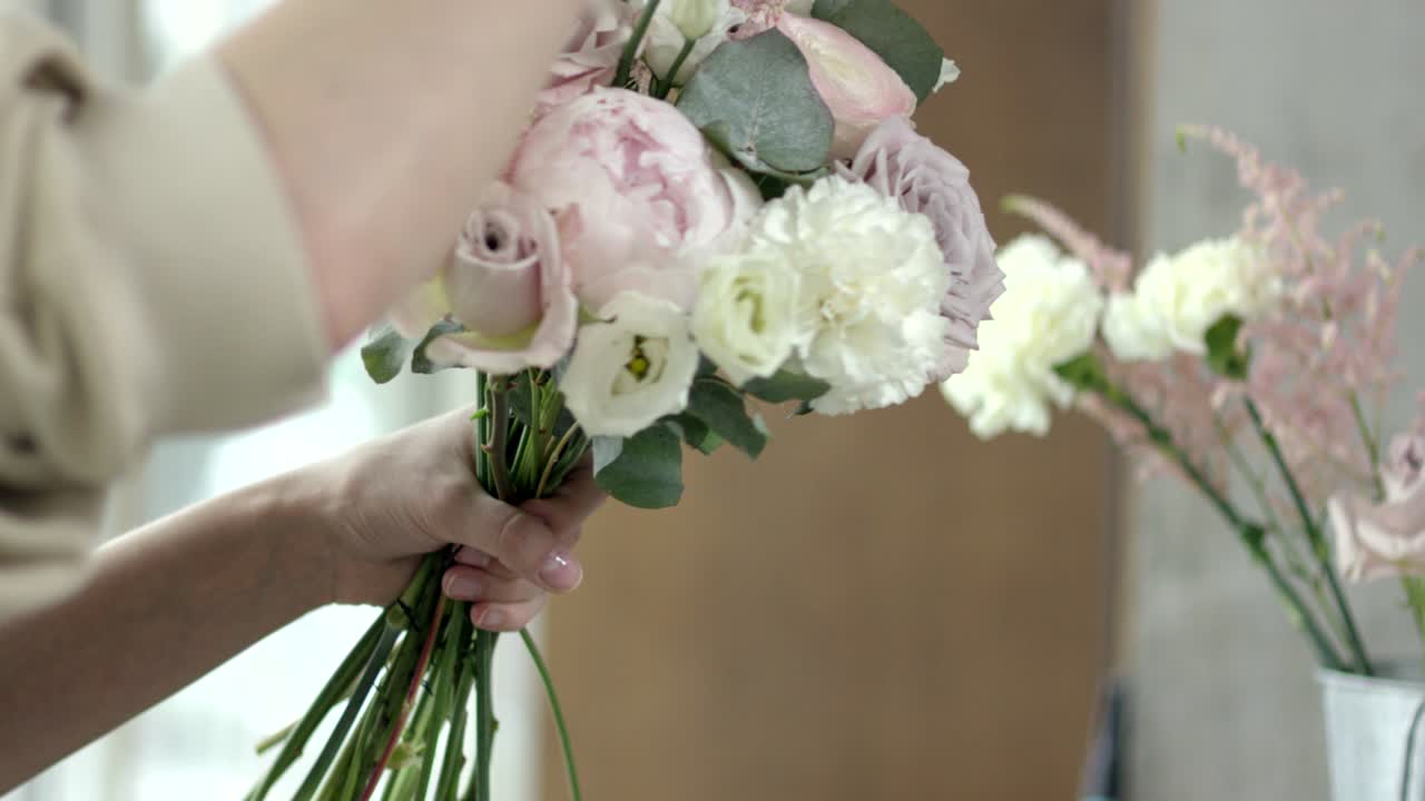 Giovane fiorista assembla un bouquet da sposa rustico.