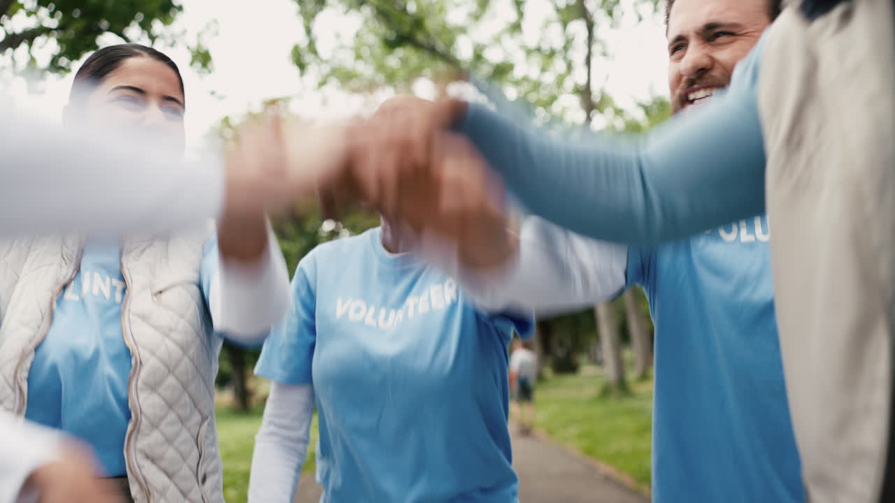 Volontari di diverse etnie che celebrano il lavoro di squadra e il successo in un parco.