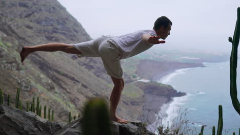 amidst the mountainous scenery, a fit young man practices sun salutation yoga, absorbing the ocean panorama. meditation and exercise converge, symbolizing a dynamic lifestyle