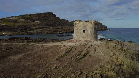 Orbital-aerial-view-of-the-tower-located-on-Isola-della-Pelosa,-Sardinia-on-a-sunny-day