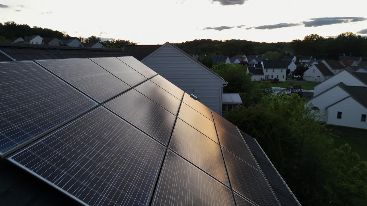 Dusk scene in american noble community. Aerial flyover shot. Solar panels array installed don roof of house. Sunset reflection on dense units. Modern and luxury houses on hilly suburb of USA.