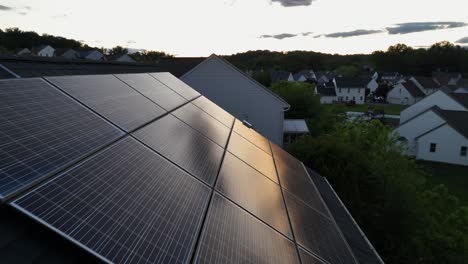 Dusk scene in american noble community. Aerial flyover shot. Solar panels array installed don roof of house. Sunset reflection on dense units. Modern and luxury houses on hilly suburb of USA.