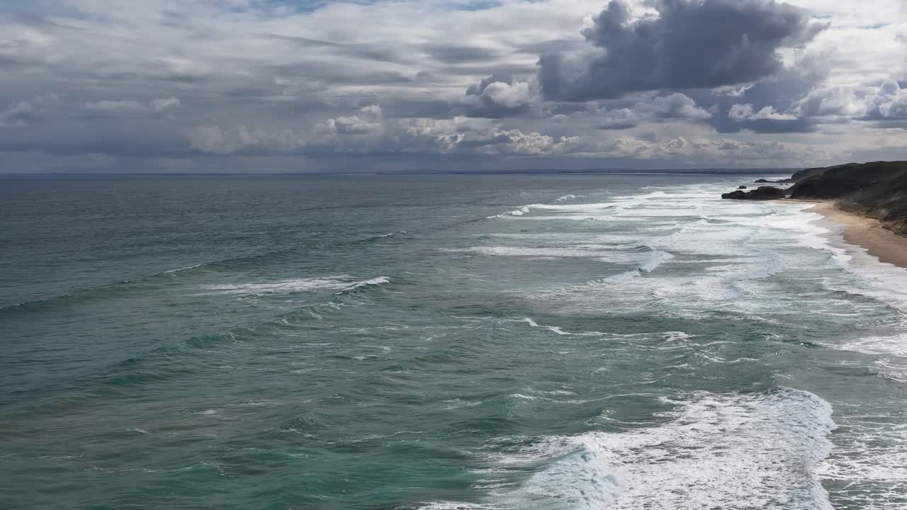 Drone captures overcast coastline, rolling waves, and dramatic sky at Portsea Beach, Victoria, Australia