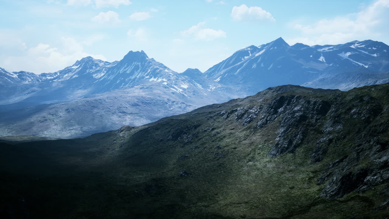 Luftaufnahme über einem Tal mit schneebedeckten Bergen in der Ferne