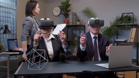 Senior-business-colleagues-using-virtual-reality-3D-app-headset-helmet-doing-research-watching-video