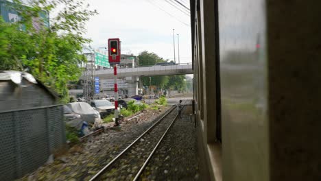 passenger view looking out window of moving train traveling through city, thailand