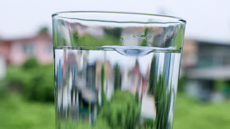 Wassertropfen-Erzeugen-Blasen-In-Einem-Glas,-Das-Mit-Sauberem-Und-Klarem-Wasser-Gefüllt-Ist