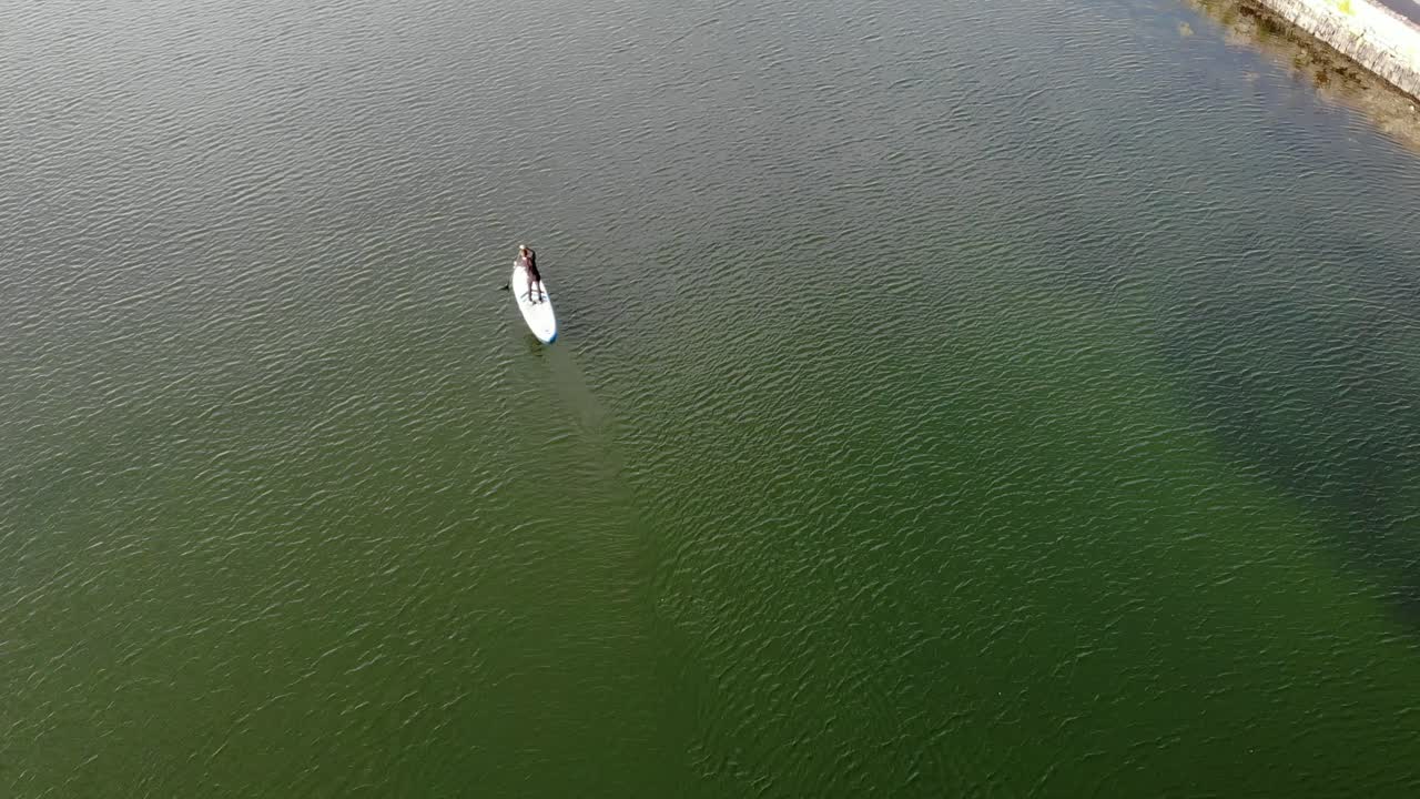 Riprese con drone di un praticante di SUP che pagaia su acqua verde
