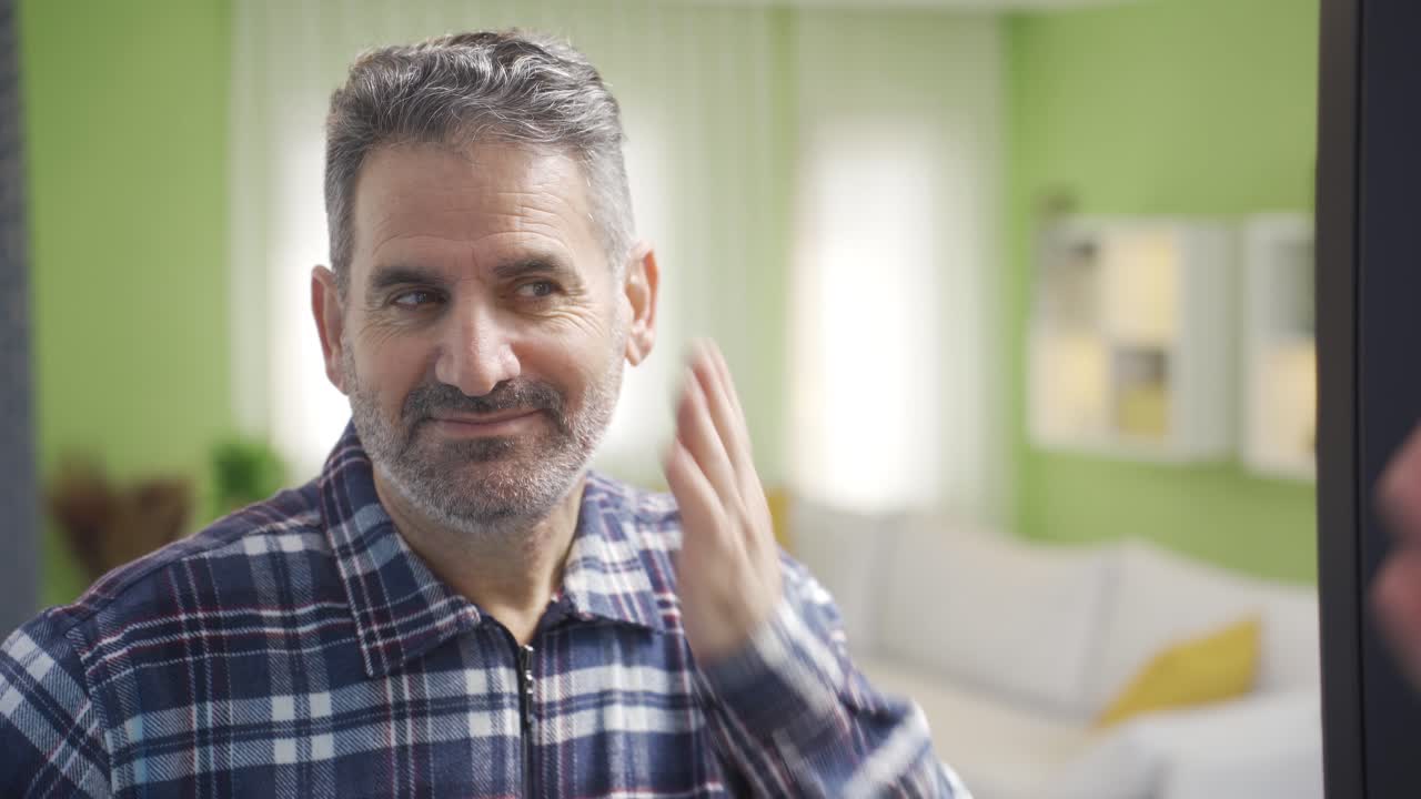 행복하고 에너지로 가득 찬 성숙한 남자는 거울에 자신을 바라보고, 자신을 사랑하고, 활기찬 기 ⁇ 을 가지고 있습니다.