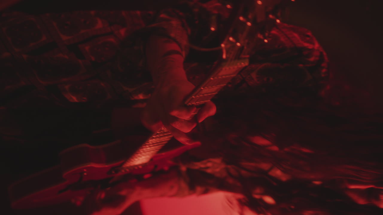 Guy Playing the Guitar and Rocking to Music in Dark Studio with Red Light