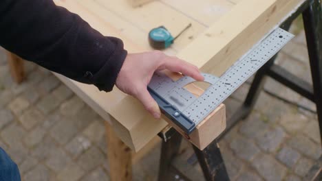 the craftsman is measuring up and marking the wood with a pen