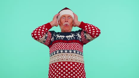 grandfather in new year deer sweater raising hands in surprise shocked by sudden victory wow emotion