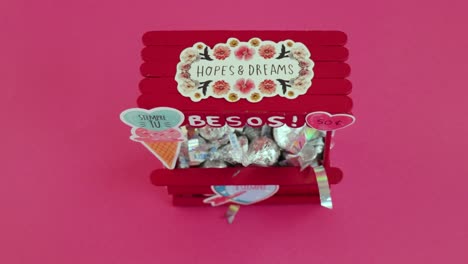 mini red kissing stand filled with candies, decorated with hearts, perfect for valentine's day gift display